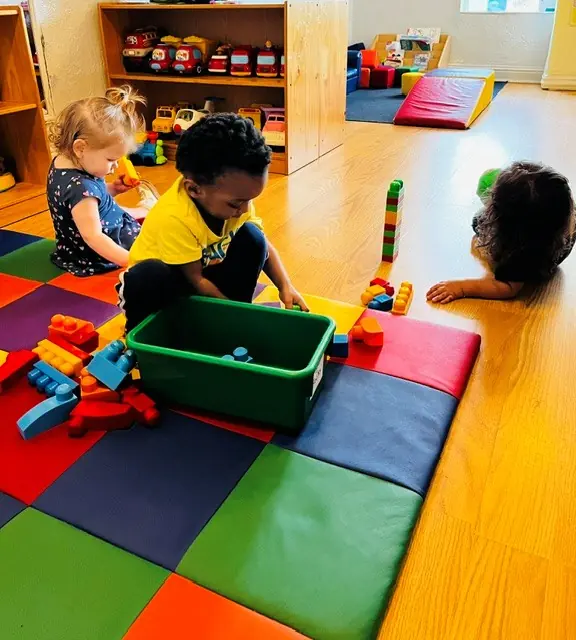 Young children building with blocks on colorful floor mats