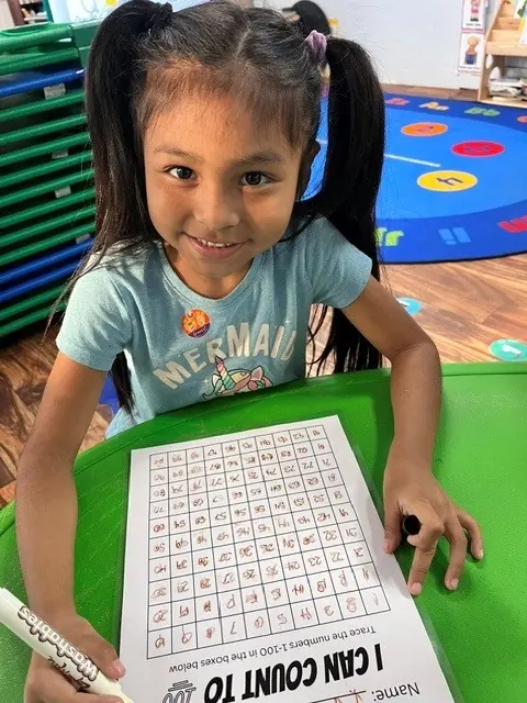 Child practicing counting with a one-to-one-hundred chart