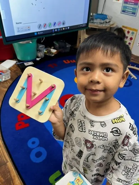 Child showing a letter M classroom activity