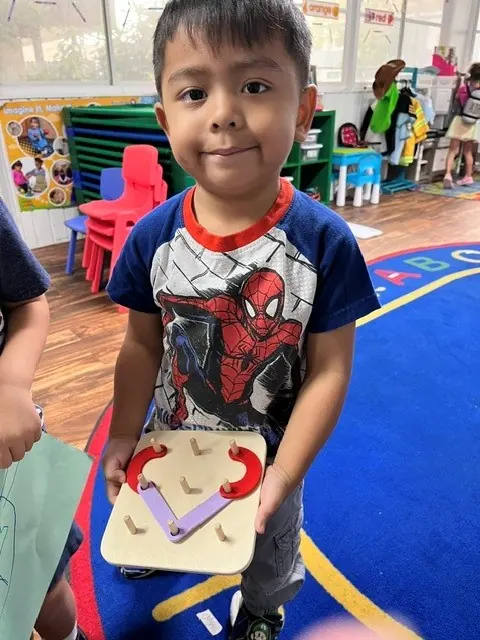 Child practicing letters with a tracing board