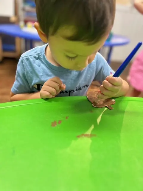 Young child creating nature-inspired art with a leaf