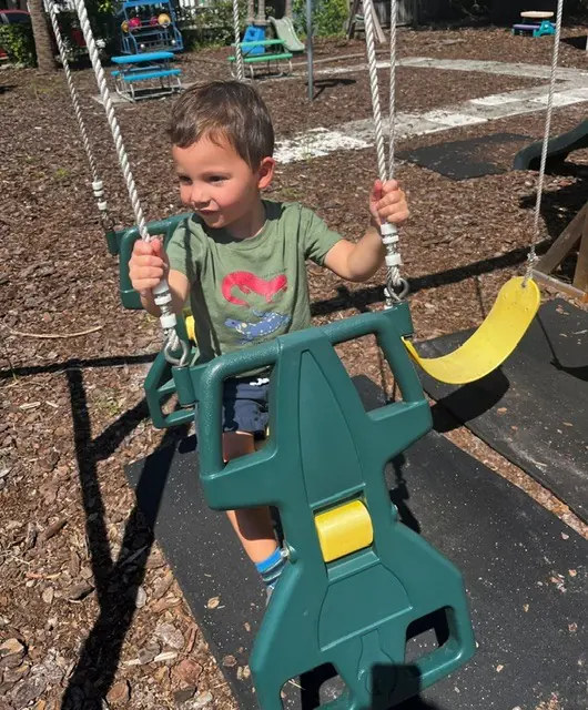 Child enjoying outdoor play on a playground swing