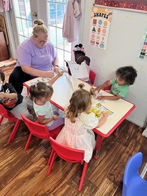 Teacher working with children in a small-group classroom activity