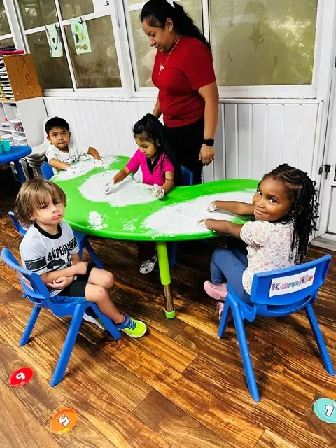 Teacher guiding children at a sensory activity table