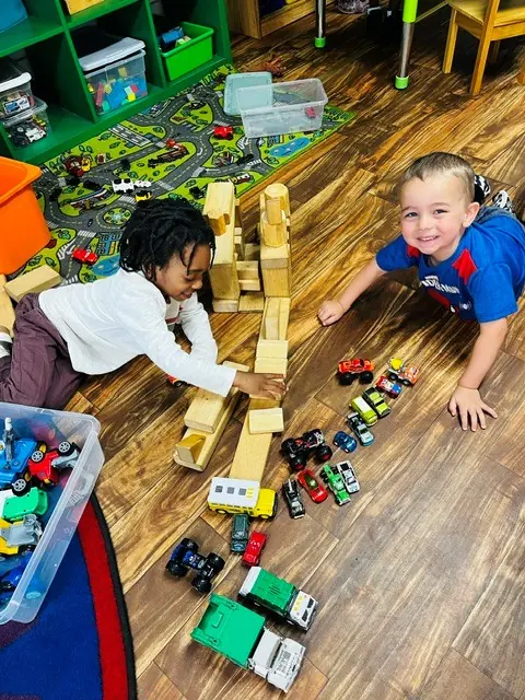 Children building with wooden blocks and toy trucks